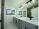 Modern bathroom featuring double sinks, gray vanity, and large mirror with ample lighting fixtures at 3920 Wisteria Pl, Punta Gorda, FL 33950