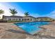 A community pool featuring a zero entry, metal handrails, and deck seating surrounded by palm trees on a sunny day at 43030 Greenway Blvd # 426, Punta Gorda, FL 33982