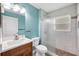 Well-lit bathroom with white tile, wood cabinet, glass shower, and blue accent wall at 8183 Deland St, Port Charlotte, FL 33981