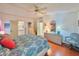 Bedroom with hardwood floors, patterned comforter, dresser, and view of the ensuite bathroom at 857 Seabrooke Dr, Englewood, FL 34223
