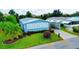 Inviting home featuring manicured landscaping, a covered carport, and colorful flowers at 857 Seabrooke Dr, Englewood, FL 34223