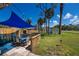 Backyard view of a patio with blue sunshade and dining set, and a shed in the distance at 900 Stewart St, Englewood, FL 34223