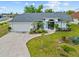 Charming home with a well-manicured lawn, decorative plants, and a paved driveway leading to an attached garage at 1 Sportsman Way, Rotonda West, FL 33947