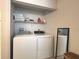 Practical laundry area with a side-by-side washer and dryer, top shelf storage, and tile floors at 10112 Willmington Blvd, Englewood, FL 34224