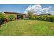 Expansive backyard with manicured lawn, mature landscaping, seating area and a beautiful, modern home at 11819 Sistine Ln, Venice, FL 34293