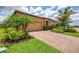 Beautiful front exterior with mature palm trees, lush landscaping, and brick paver driveway at 11819 Sistine Ln, Venice, FL 34293