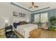 Serene main bedroom featuring tray ceilings, a ceiling fan, plantation shutters, and a cozy seating area at 11819 Sistine Ln, Venice, FL 34293