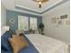 Elegant main bedroom with blue accent wall, tray ceiling, plantation shutters, and inviting decor at 11819 Sistine Ln, Venice, FL 34293