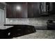 Stylish kitchen with granite countertops, dark wood cabinets, and a modern backsplash at 1480 Wise Dr, North Port, FL 34286
