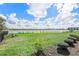 Backyard featuring a well-manicured lawn and lake views with neighborhood buildings in the distance at 17213 Bullhorn Cir, Punta Gorda, FL 33982
