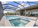 A stunning screened-in pool and spa with an outdoor kitchen, lounge seating, and a beautiful backyard at 17213 Bullhorn Cir, Punta Gorda, FL 33982