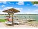 Waterfront scene with boat rack, dock, and sandy beach area under a bright blue, cloudy sky at 17213 Bullhorn Cir, Punta Gorda, FL 33982