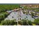 Aerial view of community tennis courts, a pool and clubhouse near a wooded area at 181 Padova Way # 19, Nokomis, FL 34275