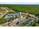 Aerial view of the community pool, tennis courts and clubhouse surrounded by trees at 181 Padova Way # 19, Nokomis, FL 34275