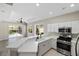 Bright kitchen boasts white cabinetry, stainless steel appliances, and convenient counter space overlooking the pool area at 181 Padova Way # 19, Nokomis, FL 34275