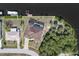 Aerial view featuring a waterfront home with screened pool, surrounded by tropical foliage and canal at 18602 Ashcroft Cir, Port Charlotte, FL 33948