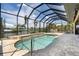 Enjoy this covered outdoor pool area featuring lush landscaping and waterfront views at 18602 Ashcroft Cir, Port Charlotte, FL 33948