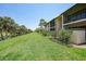 Exterior view of the condo building with screened lanais, green space, and palm trees at 19505 Quesada Ave # M104, Port Charlotte, FL 33948