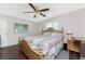 Bright bedroom showcasing a wooden bed, ceiling fan, natural light, and neutral decor at 2008 Pellam Blvd, Port Charlotte, FL 33948