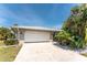 View of a two-car garage situated on a well-maintained driveway surrounded by lush, mature tropical landscaping at 2008 Pellam Blvd, Port Charlotte, FL 33948