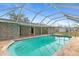 Backyard in-ground pool with a screened enclosure, and a stone block house at 20167 Rutherford Ave, Port Charlotte, FL 33952
