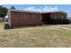 Single story home with a brick facade and orange shutters sitting on a large lawn at 2328 Picnic St, Port Charlotte, FL 33952