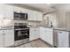 Updated kitchen showcasing stainless steel appliances, granite countertops, and white cabinetry at 2381 Sheila Ln, North Port, FL 34286