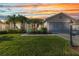 Charming single-story home featuring lush lawn, mature landscaping, and a two-car garage at sunset at 24371 Folkstone Ave, Punta Gorda, FL 33980