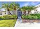 Beautifully landscaped front entrance with a stylish screen door, lush plants, and green grass at 24371 Folkstone Ave, Punta Gorda, FL 33980