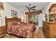 Comfortable main bedroom features a wooden bed frame, ceiling fan, sliding glass doors, and wood-look laminate flooring at 24371 Folkstone Ave, Punta Gorda, FL 33980
