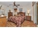 Well-lit main bedroom features a large bed, ceiling fan, wooden furniture, and sliding glass doors at 24371 Folkstone Ave, Punta Gorda, FL 33980