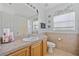 Well-lit bathroom with a sink, toilet, mirror and neutral color tile at 27038 San Jorge Dr, Punta Gorda, FL 33983