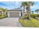 Inviting single-story home featuring a two-car garage, brick driveway, and palm tree landscaping at 281 Potenza Loop, Nokomis, FL 34275