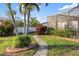 Landscaped backyard featuring a stone path, lush lawn, shade trees, and screened lanai for relaxation at 3301 Santa Barbara Dr, Punta Gorda, FL 33983