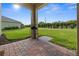 Relaxing covered patio with brick flooring and a view of the lush green backyard and landscaping at 3941 River Bank Way, Punta Gorda, FL 33980