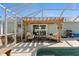Cozy outdoor patio space featuring a wooden pergola, comfortable seating, and direct access to the sparkling pool area at 6286 Coniston St, Port Charlotte, FL 33981