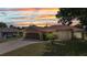 Charming single-story home with well-manicured lawn, attached garage, and security gate at entry under a colorful sunset sky at 78 Zenith St, Port Charlotte, FL 33954