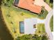 Aerial view of a home featuring a screened pool, lush landscaping, and tile roof in a waterfront community at 13284 Amaryllis Cir, Port Charlotte, FL 33981