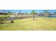 Waterfront backyard featuring lush green grass, landscaping, and water views at 13284 Amaryllis Cir, Port Charlotte, FL 33981