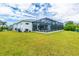 Wide open green backyard featuring a large screened in pool enclosure at 13284 Amaryllis Cir, Port Charlotte, FL 33981