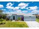 Inviting single-story home featuring a three-car garage, lush lawn, and vibrant, colorful landscaping at 13284 Amaryllis Cir, Port Charlotte, FL 33981