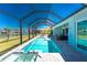 A beautiful screened-in pool with a spa and waterfront views under a bright blue sky at 13284 Amaryllis Cir, Port Charlotte, FL 33981