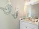 Charming powder room with a vanity, mirror, and coastal decorations on the wall at 13284 Amaryllis Cir, Port Charlotte, FL 33981