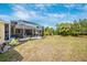 Expansive backyard featuring a screened-in porch with an adjacent wooded area and blue skies at 13325 Ketridge Ave, Port Charlotte, FL 33953