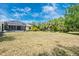 Large backyard showing the exterior of the screened in porch with an adjacent wooded area at 13325 Ketridge Ave, Port Charlotte, FL 33953