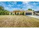 Charming yellow home featuring an American flag, well-maintained landscaping, and attached garage at 13325 Ketridge Ave, Port Charlotte, FL 33953