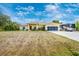 Well-manicured lawn leads up to a charming yellow house, complete with screened garage and RV parking at 13325 Ketridge Ave, Port Charlotte, FL 33953