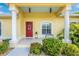 Charming home entrance featuring a red door, decorative shrubbery, and classic architectural details at 13325 Ketridge Ave, Port Charlotte, FL 33953