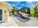 Side view of RV parking showing a concrete driveway and gravel parking spot, adjacent to a yellow house at 13325 Ketridge Ave, Port Charlotte, FL 33953
