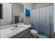 Bathroom featuring granite countertop, decorative mirror and lighting above vanity, toilet with blue shower curtain at 16440 Marsh Ln, Punta Gorda, FL 33982